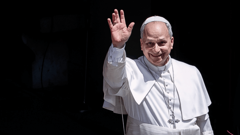 Papa Leão XIV sorri e acena aos fiéis durante aparição em Castel Gandolfo, vestindo batina branca, solidéu e cruz peitoral.