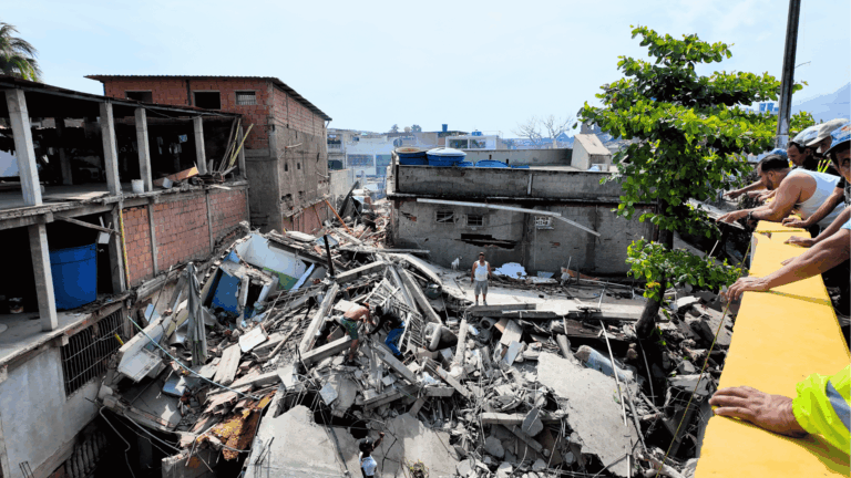 Área destruída por terremoto em La Guaira, na Venezuela, com edifícios desabados, equipes e moradores sobre os escombros durante as buscas por vítimas.