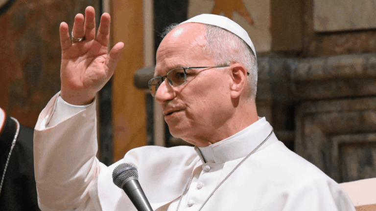 apa Leão XIV, usando vestes brancas e óculos, com os braços erguidos durante audiência no Vaticano.