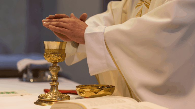 Padre com as mãos unidas sobre um cálice durante a consagração eucarística na celebração da Santa Missa.