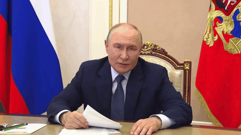Vladimir Putin sentado, apoiado em uma mesa, segurando papéis.
